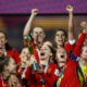 Spain women's national football team players smiling and cheering together while lifting the trophy in celebration after winning the FIFA Women's World Cup. Image used for Sportxparte news.