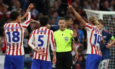 Atlético Madrid players Marc Pubill (#18), Johnny Cardoso (#5), and Marcos Llorente (#14) are protesting a decision by referee Danny Makkelie during their UEFA Champions League semi-final first leg against Arsenal. Image used for Sportxparte news.