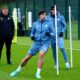 Newcastle United midfielder Sandro Tonali (center) performing agility drills during a training session at the club's Benton base. He is wearing a blue long-sleeved training top and matching shorts. Standing behind him is teammate Bruno Guimarães in similar blue training gear and a black beanie, while manager Eddie Howe watches from the side in a black Castore training jacket. Image used for Sportxparte news.