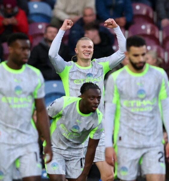 Manchester City forward Erling Haaland (center) celebrates with his arms raised after scoring the decisive goal in a 1-0 victory against Burnley at Turf Moor on April 22, 2026. He is joined in the foreground by teammates Jérémy Doku (front center), who provided the assist. Image used for Sportxparte news.