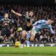 Manchester City striker Erling Haaland (right, in light blue) is being challenged by Leeds United defender Pascal Struijk (center, in black/patterned kit). Leeds player James Justin is also visible on the left. Image used for Sportxparte news.