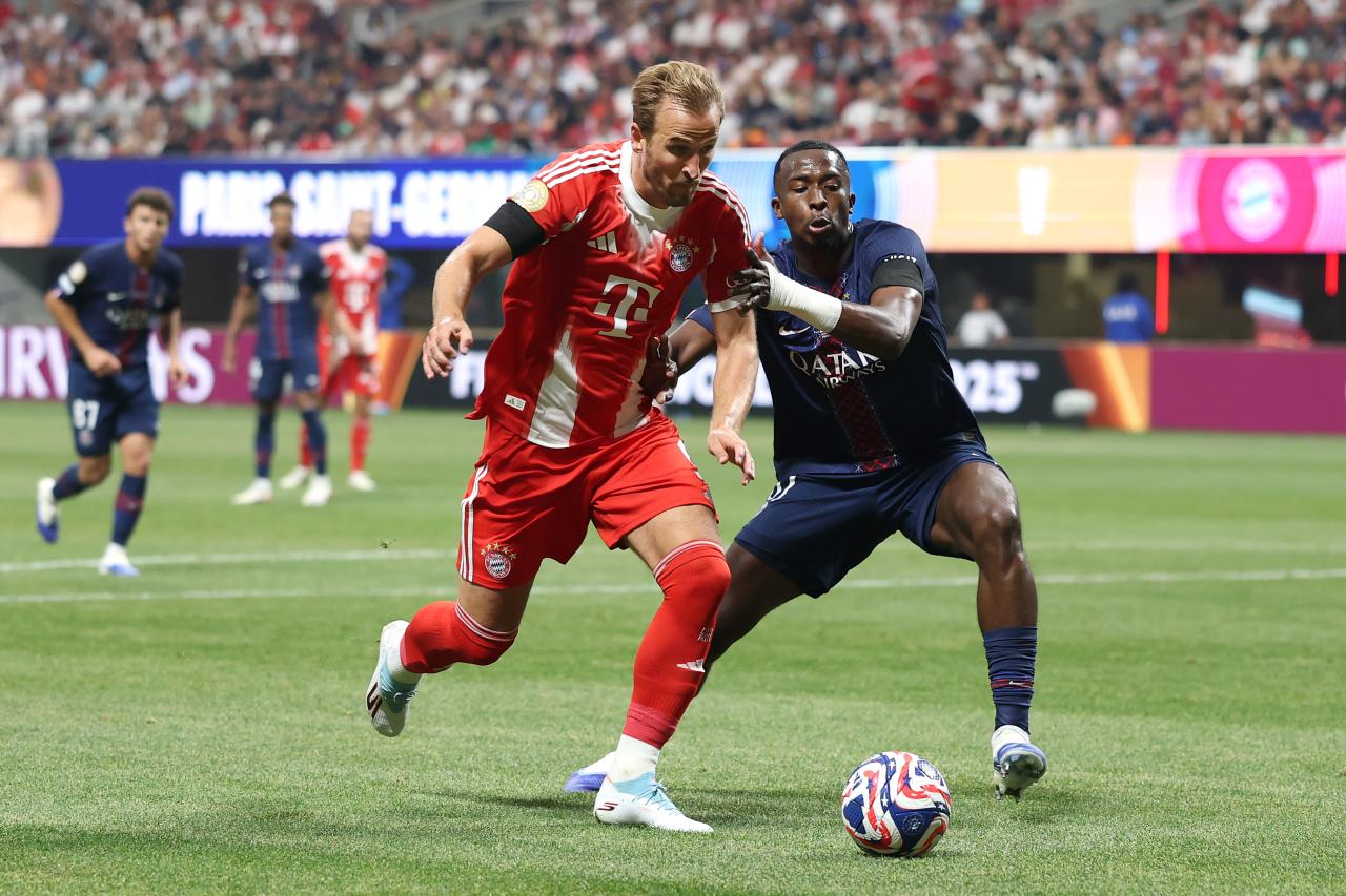 Harry Kane of Bayern Munich (left) in a duel with Willian Pacho of Paris Saint-Germain (right). The photograph captures action from a high-stakes meeting between the two European giants, likely from their FIFA Club World Cup quarter-final clash in July 2025. Image used for Sportxparte