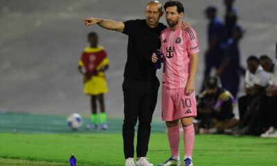 Lionel Messi and coach Javier Mascherano on the pitch in the Inter Miami 24/25 Home Authentic Jersey. Messi wears the pink "Euforia" kit with his iconic number 10, standing next to Mascherano in all-black sideline gear during an Inter Miami CF match. Image used for Sportxparte news.