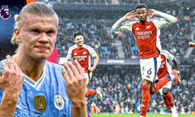 An action-oriented promotional graphic featuring Erling Haaland of Manchester City on the left, looking intense and celebrating, and Gabriel Magalhães of Arsenal on the right, running and celebrating a goal. In the background, another Arsenal player is visible on the pitch in a crowded stadium during a rainy match day. The Premier League logo is positioned in the top left corner. Image used for Sportxparte news.