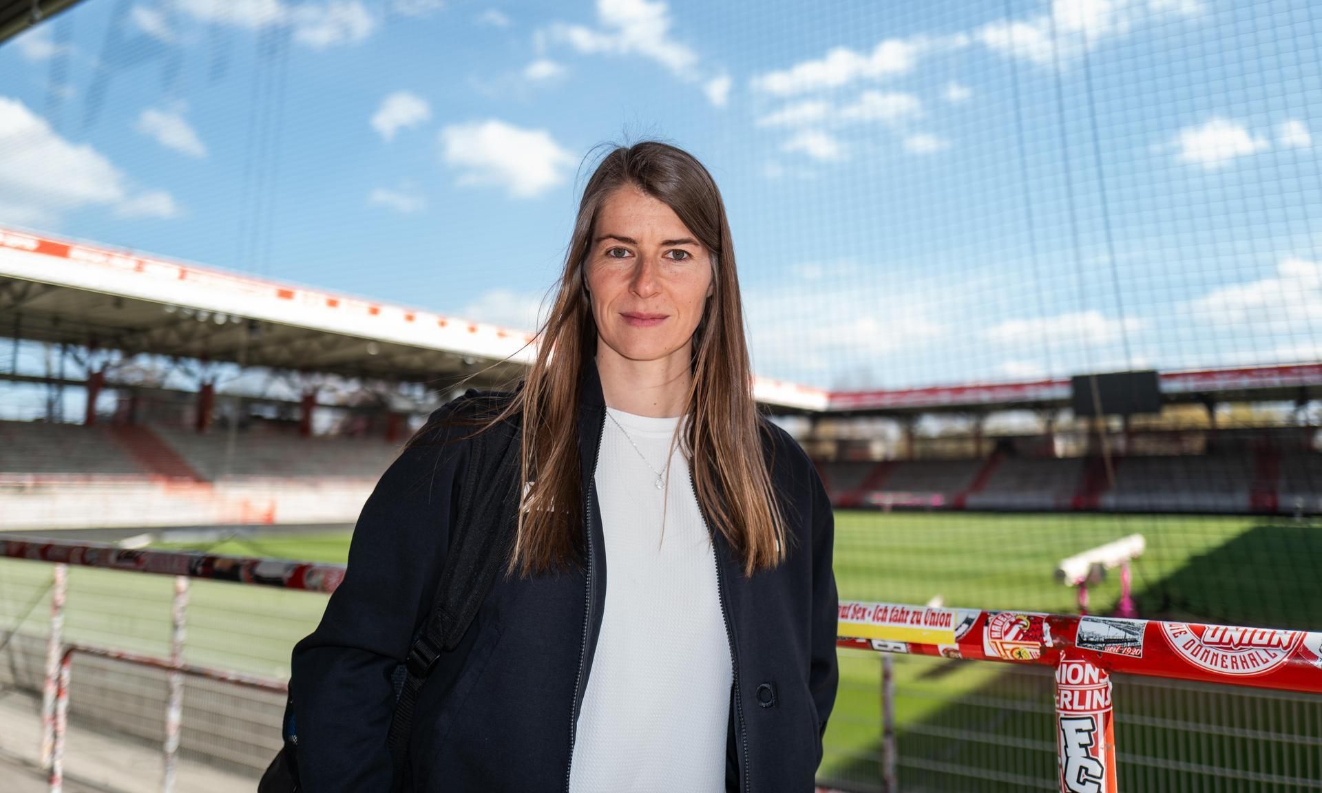 Marie-Louise Eta, the first female head coach in Bundesliga history, is standing at the FC Union Berlin stadium. Image used for Sportxparte news.