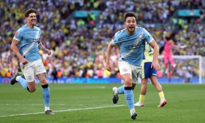 Nico González of Manchester City is celebrating a decisive late goal during a 2-1 victory over Southampton in the FA Cup semi-final. Behind him to the left, teammate John Stones joins in the celebration. Image used for Sportxparte news roundup.