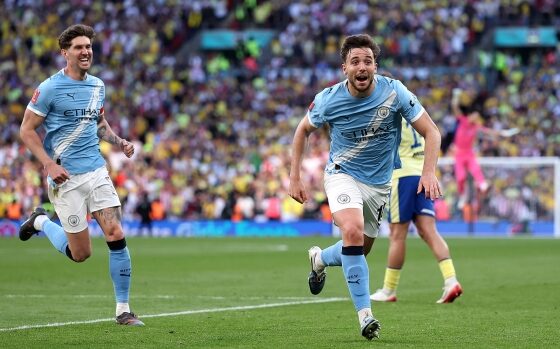 Nico González of Manchester City is celebrating a decisive late goal during a 2-1 victory over Southampton in the FA Cup semi-final. Behind him to the left, teammate John Stones joins in the celebration. Image used for Sportxparte news roundup.