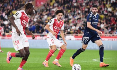 The image captures a Ligue 1 football match between AS Monaco and Paris FC. The featured players include Maghnes Akliouche (center, wearing #11) and George Ilenikhena (left, wearing #28) for AS Monaco, and Pierre Lees-Melou (right, wearing #33) for Paris FC. Image used for Sportxparte news