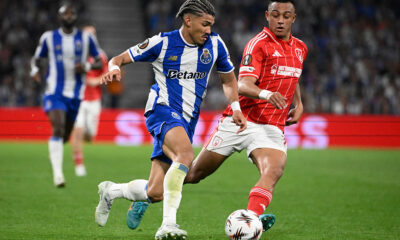 FC Porto winger William Gomes in a blue and white striped kit controls the ball while being pursued by a Nottingham Forest player in a red pinstriped kit during their 2025/26 UEFA Europa League quarterfinal at the Estádio do Dragão. Image used for Sportxparte news.