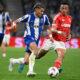 FC Porto winger William Gomes in a blue and white striped kit controls the ball while being pursued by a Nottingham Forest player in a red pinstriped kit during their 2025/26 UEFA Europa League quarterfinal at the Estádio do Dragão. Image used for Sportxparte news.