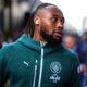 A close-up of professional footballer Antoine Semenyo wearing a teal Manchester City training hoodie. He is looking off-camera to his right with a focused expression, and a white wireless earbud is visible in his ear. Image used for Sportxparte news.