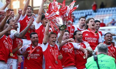 Arsenal captain Martin Ødegaard hoisting the Premier League trophy surrounded by his ecstatic teammates following the final match of the 2025–26 season. Image used for Sportxparte news.