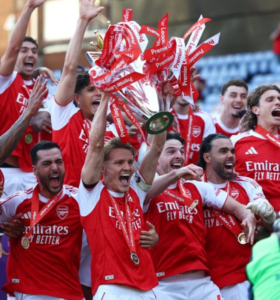 Arsenal captain Martin Ødegaard hoisting the Premier League trophy surrounded by his ecstatic teammates following the final match of the 2025–26 season. Image used for Sportxparte news.