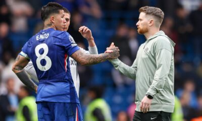 Chelsea midfielder Enzo Fernández (wearing the blue number 8 jersey) shakes hands and converses with interim head coach Calum McFarlane (in a grey Chelsea training hoodie) on a football pitch during a match day. Image used for Sportxparte news.