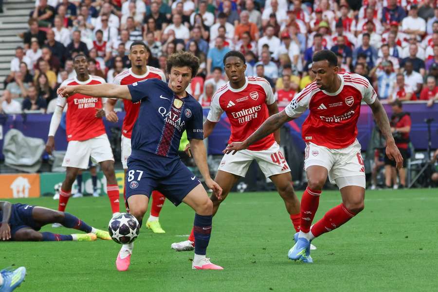 João Neves (wearing the number 87 kit for Paris Saint-Germain) drives the ball past Arsenal defender Cristhian Mosquera (number 49) and center-back Gabriel Magalhães (number 6). Image used for Sportxparte news.