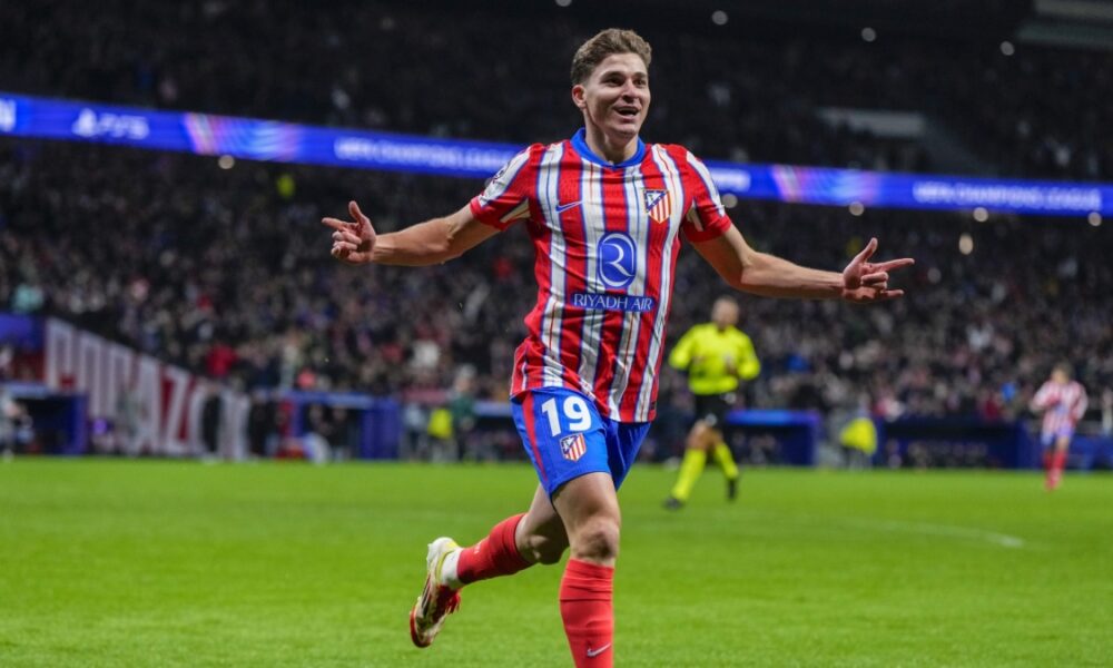 Atlético Madrid forward Julián Álvarez celebrates a goal on the pitch during a match. He wears the club's traditional red-and-white striped jersey with blue shorts emblazoned with the number 19. Image used for Sportxparte news.