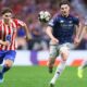 An action shot from a football match featuring Declan Rice of Arsenal and Julián Álvarez of Atlético Madrid competing for the ball. Rice, on the right, is wearing a dark blue and red Arsenal away kit, while Álvarez, on the left, is in Atlético’s traditional red-and-white striped home jersey. Image used for Sportxparte news Preview.