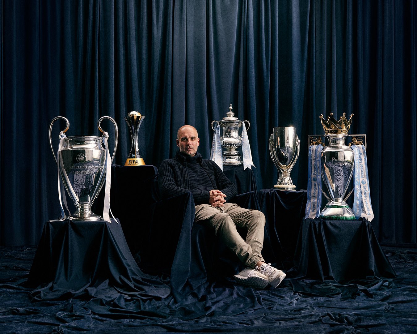 Pep Guardiola, the manager of Manchester City Football Club, is posing with the five major trophies won during the 2022/2023 season. Image used for Sportxparte news.