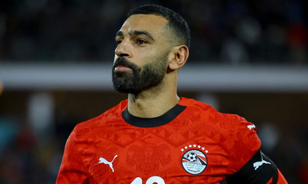 Mohamed Salah representing the Egyptian National Football Team. He is seen sporting a shorter hairstyle and trimmed beard while wearing the official Egyptian red Puma national jersey. Image used for Sportxparte news.