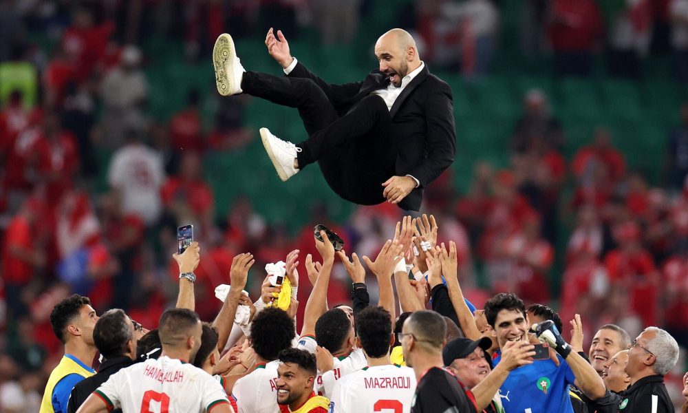 Moroccan national football team players enthusiastically throw their manager, Walid Regragui, into the air in celebration on the pitch. Image used for Sportxparte news.