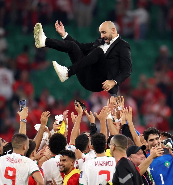 Moroccan national football team players enthusiastically throw their manager, Walid Regragui, into the air in celebration on the pitch. Image used for Sportxparte news.