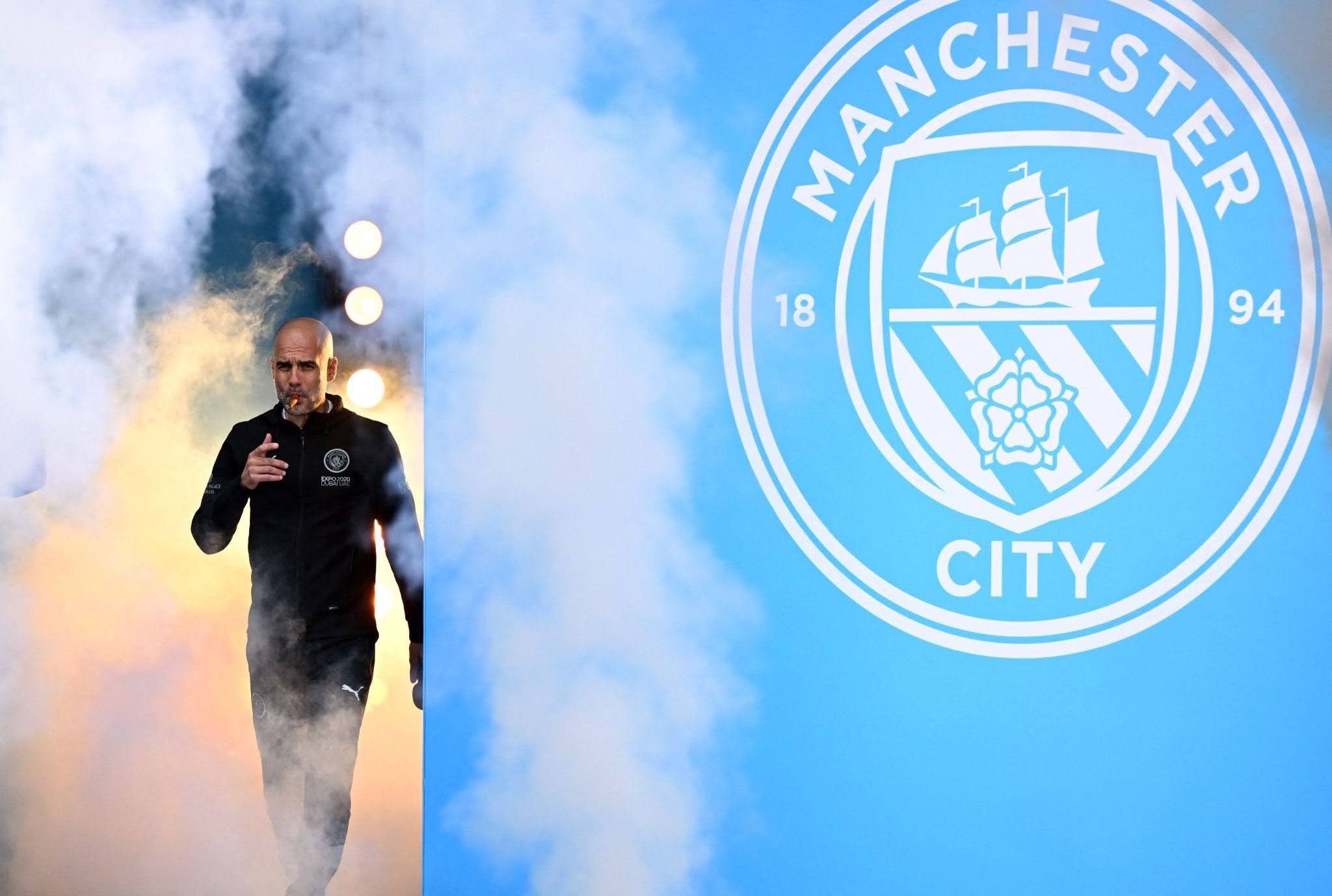 Pep Guardiola, the manager of Manchester City Football Club, walks through thick smoke during a celebration or event. Image used for Sportxparte news.
