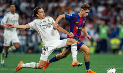 Real Madrid's Alvaro Carreras (#18) performing a sliding tackle on FC Barcelona's Fermin Lopez during the El Clásico La Liga match at the Santiago Bernabéu. Image used for Sportxparte news.