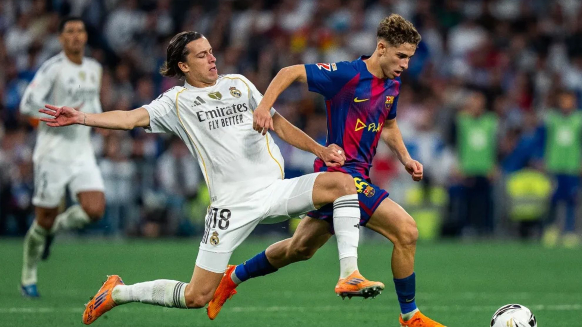 Real Madrid's Alvaro Carreras (#18) performing a sliding tackle on FC Barcelona's Fermin Lopez during the El Clásico La Liga match at the Santiago Bernabéu. Image used for Sportxparte news.