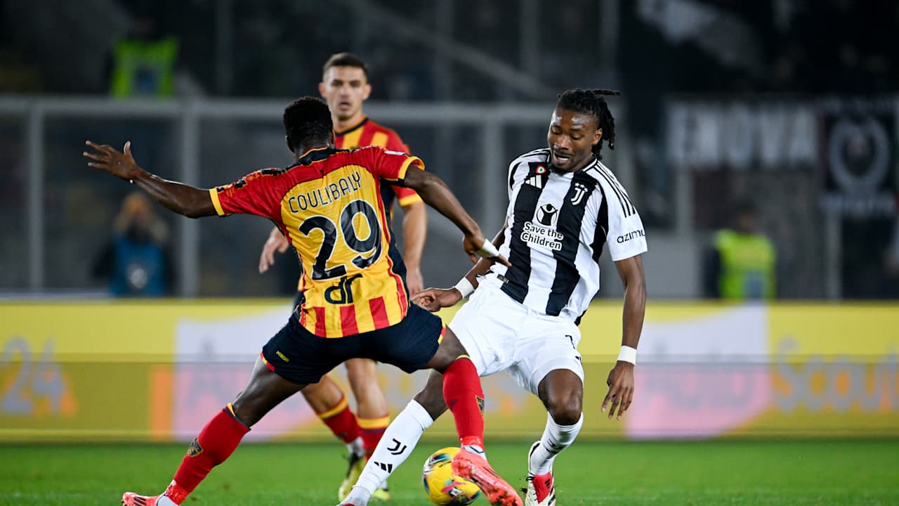 Serie A football match showing Khéphren Thuram of Juventus in a black-and-white striped jersey dribbling the ball. He is being closely defended from behind by Lameck Banda of US Lecce, who is wearing a yellow and red striped kit with the number 29. Image used for Sportxparte news.