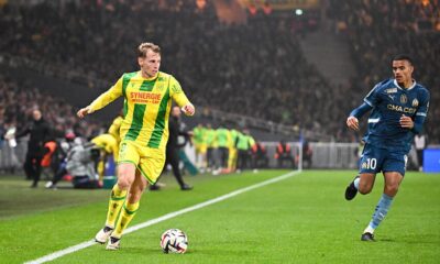 The player in the yellow and green kit is Nicolas Cozza of FC Nantes. The player in the blue kit is Mason Greenwood of Olympique de Marseille, wearing his characteristic number 10. Image used for Sportxparte preview news.