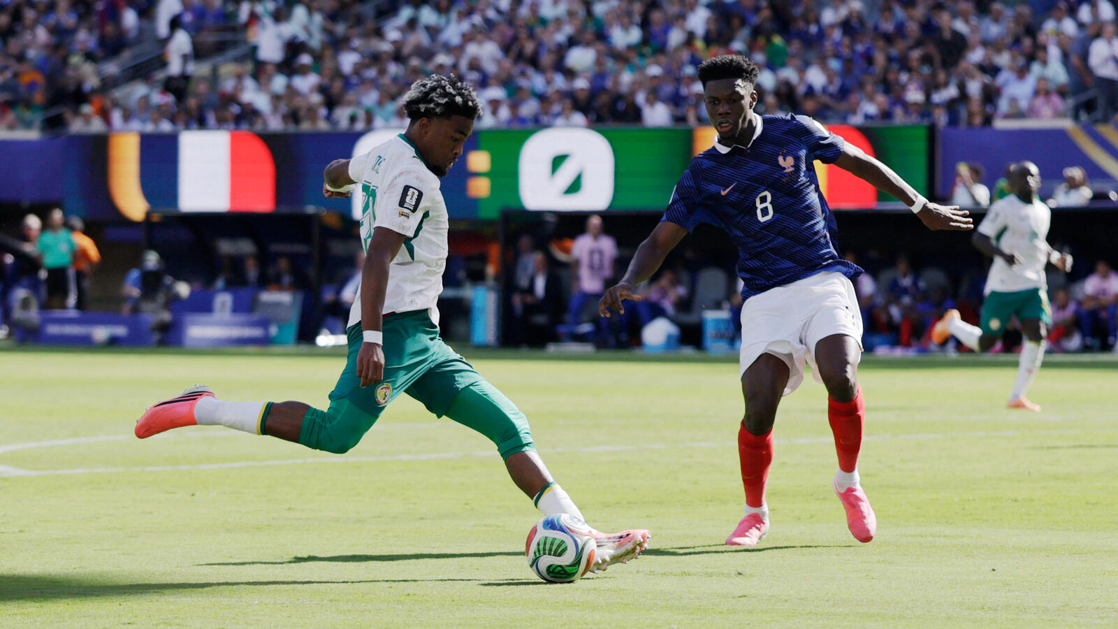 France midfielder Aurélien Tchouaméni in a dark blue jersey tracks and defends against Senegal winger Ibrahim Mbaye in a white and green kit as he controls the ball on the pitch during their Group I opening match at the FIFA World Cup 2026 inside MetLife Stadium. Image used for Sportxparte news