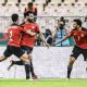 Mohamed Salah is celebrating with his teammates Mohamed Abdelmonem (left) and Trézéguet (right) during the Egypt national football team's extra-time victory over Morocco in the AFCON quarterfinals. Image used for Sportxparte news.