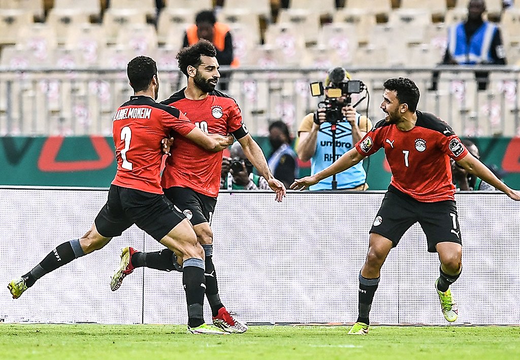 Mohamed Salah is celebrating with his teammates Mohamed Abdelmonem (left) and Trézéguet (right) during the Egypt national football team's extra-time victory over Morocco in the AFCON quarterfinals. Image used for Sportxparte news.