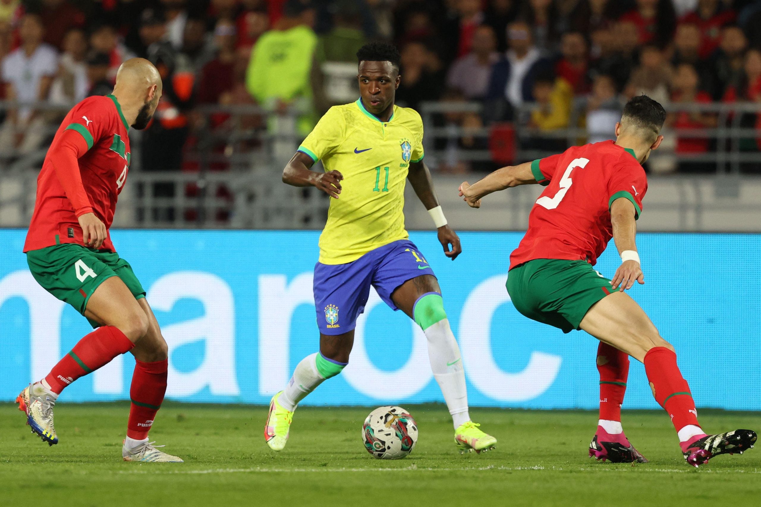 Vinícius Júnior, wearing the number 11 yellow jersey for Brazil, is captured here during an international friendly against Morocco. The match took place on March 25, 2023, at the Ibn Batouta Stadium in Tangier, Morocco. Image used for Sportxparte news.