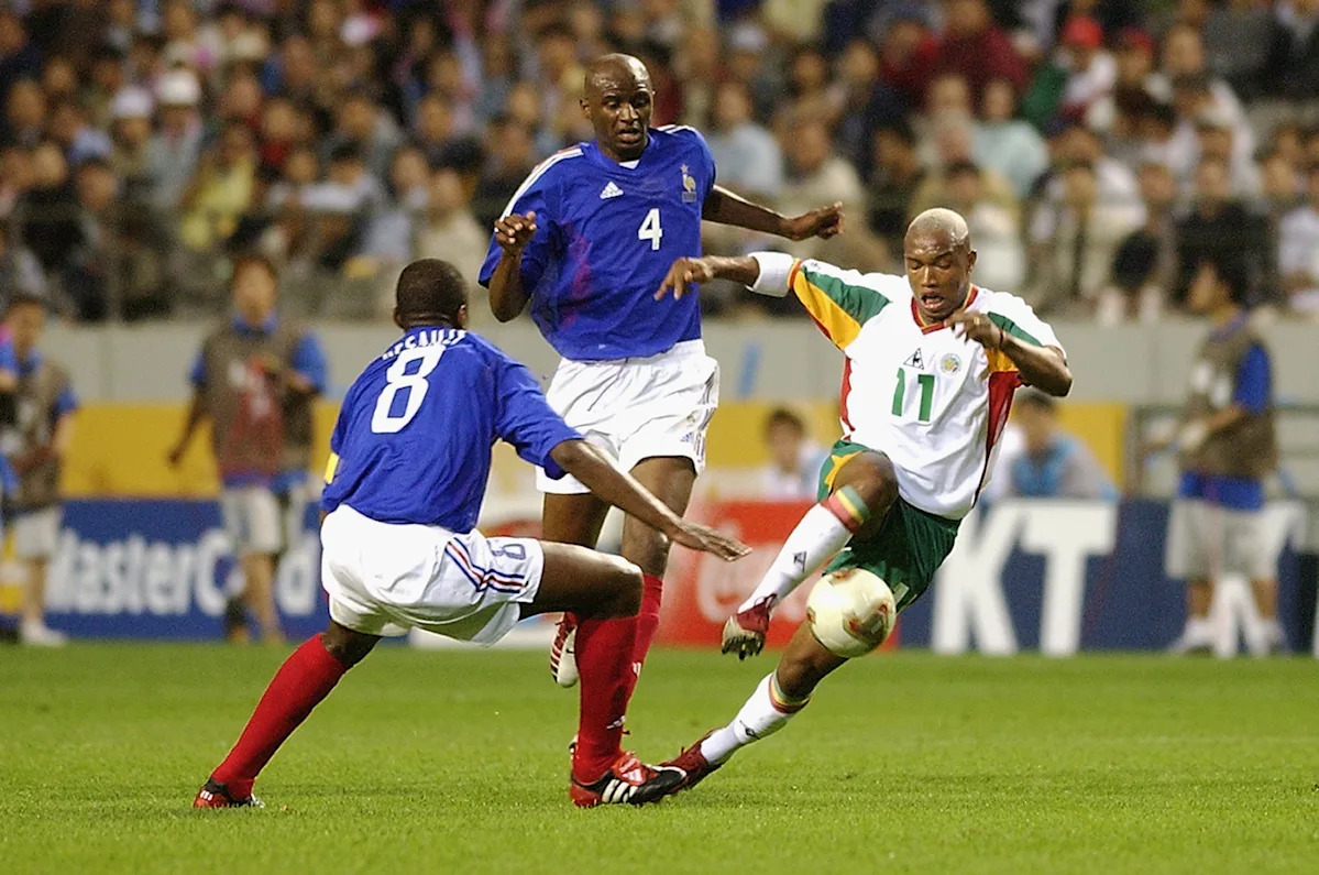 Senegal's El Hadji Diouf driving the ball past France's Patrick Vieira (No. 4) and Marcel Desailly (No. 8) during the opening match of the 2002 FIFA World Cup. Image used for Sportxparte news.
