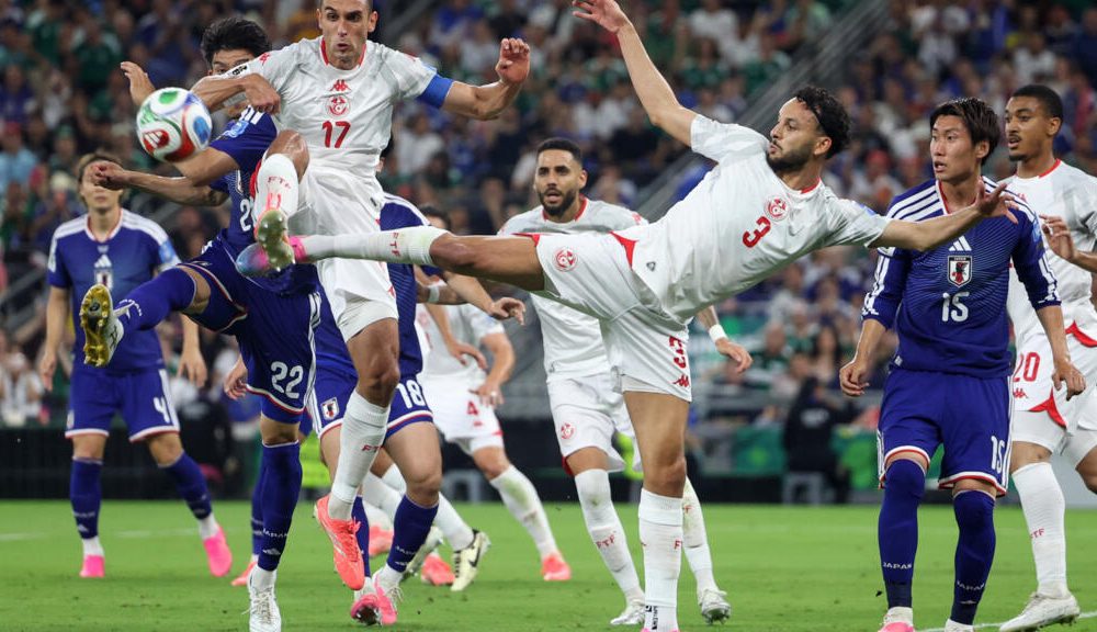 Tunisia's Montassar Talbi #3 and Ellyes Skhiri #17 battle mid-air with Japan's Takehiro Tomiyasu #22 for a soccer ball during the 1,000th World Cup match. Image used for Sportxparte news.