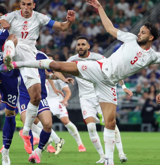 Tunisia's Montassar Talbi #3 and Ellyes Skhiri #17 battle mid-air with Japan's Takehiro Tomiyasu #22 for a soccer ball during the 1,000th World Cup match. Image used for Sportxparte news.