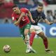 Kylian Mbappé of France wearing a blue Nike jersey and Achraf Hakimi of Morocco wearing a red Puma kit during the 2022 World Cup semi-final. Image used for Sportxparte news.