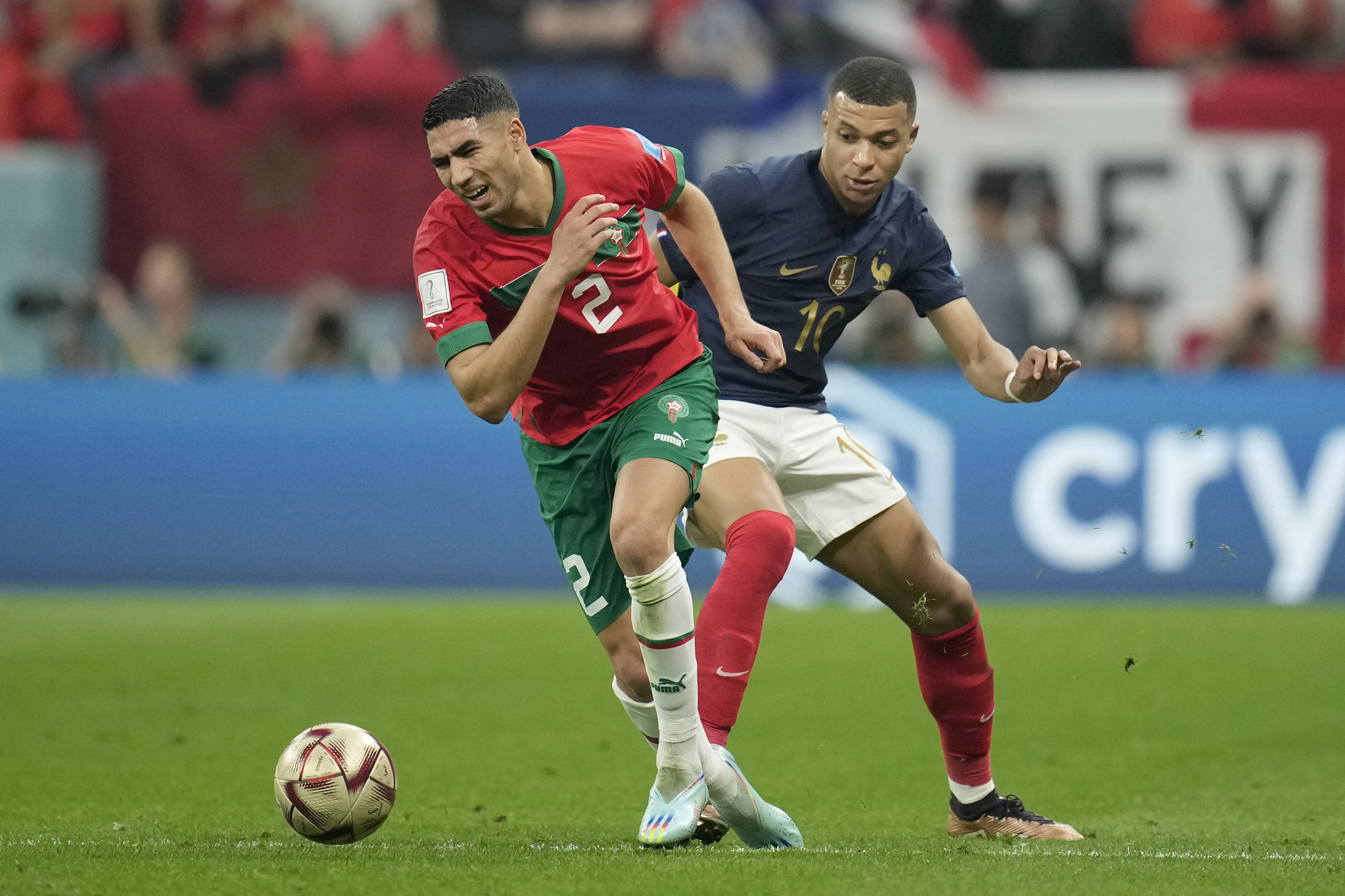 Kylian Mbappé of France wearing a blue Nike jersey and Achraf Hakimi of Morocco wearing a red Puma kit during the 2022 World Cup semi-final. Image used for Sportxparte news.