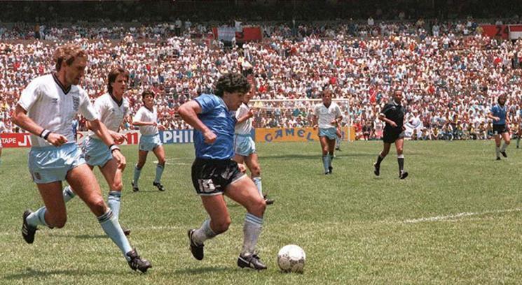Diego Maradona dribbling past English defenders during the iconic Argentina v England quarterfinal match at the 1986 FIFA World Cup. Taken on June 22, 1986, at the Estadio Azteca in Mexico City, this specific moment shows Maradona embarking on his famous solo run to score what was later voted the "Goal of the Century. Image used for Sportxparte news.