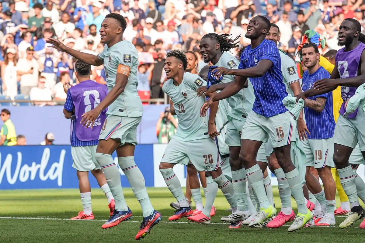 The France national football team is celebrating its 2-0 victory against Morocco in the quarterfinals of the FIFA World Cup 2026™. The match took place at Boston Stadium in Foxborough, Massachusetts. Key players such as Kylian Mbappé, Désiré Doué (number 20), and Ibrahima Konaté (number 15) are pictured in their light mint green kit celebrating alongside teammates on the pitch. Image used for Sportxparte news.