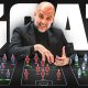 A graphic thumbnail featuring football manager Pep Guardiola smiling and leaning over three tactical football formation boards laid out horizontally against a dark background with the word "GOAT" in massive, bold white letters behind him. From left to right, the boards depict miniaturized player figures arranged in tactical shapes representing his main coaching eras: his Barcelona team in blue and red stripes, his Bayern Munich side in solid red kits, and his Manchester City squad in light blue jerseys, complete with glowing green tactical movement arrows. Image used for Sportxparte news.