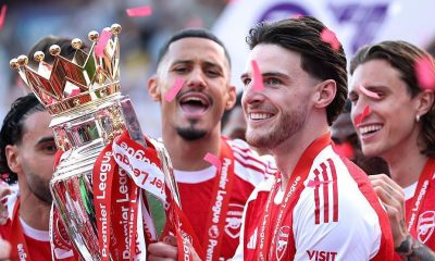 Arsenal midfielder Declan Rice celebrating with teammates after winning the Premier League trophy in May 2026, ending the club's 22-year wait for the league title. Image used for Sportxparte news.