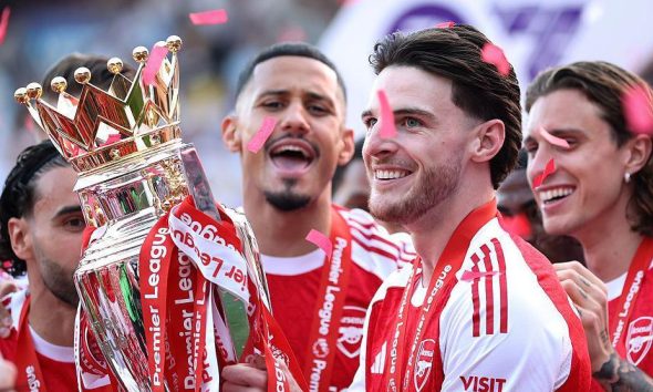 Arsenal midfielder Declan Rice celebrating with teammates after winning the Premier League trophy in May 2026, ending the club's 22-year wait for the league title. Image used for Sportxparte news.
