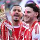 Arsenal midfielder Declan Rice celebrating with teammates after winning the Premier League trophy in May 2026, ending the club's 22-year wait for the league title. Image used for Sportxparte news.