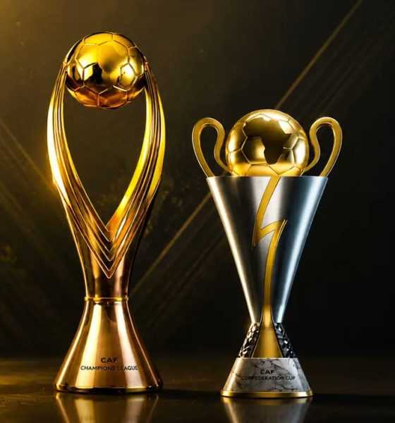 The official golden CAF Champions League trophy next to the silver and gold CAF Confederation Cup trophy on a dark backdrop. Image used for Sportxparte news.
