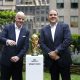 FIFA President Gianni Infantino and Vice President Vittorio Montagliani posing with the official golden FIFA World Cup Winner’s Trophy on a white pedestal during a New York broadcast event. Image used for Sportxparte news.