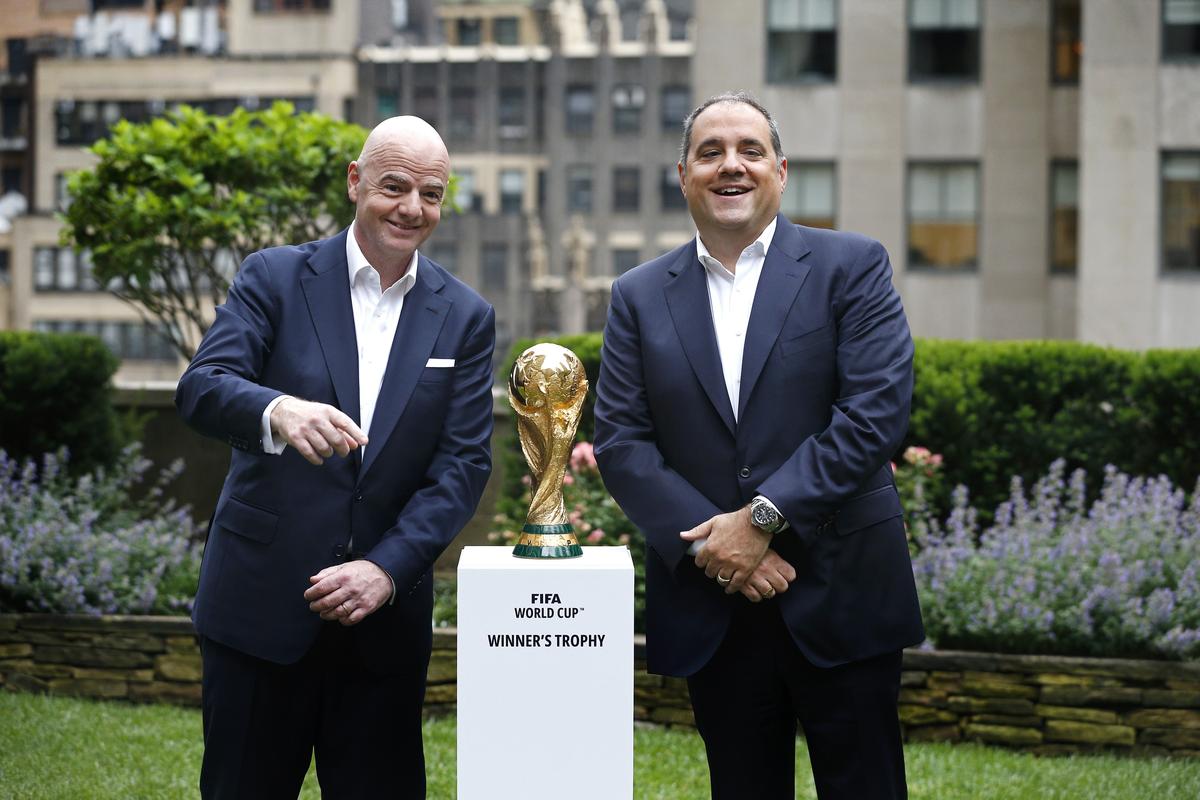 FIFA President Gianni Infantino and Vice President Vittorio Montagliani posing with the official golden FIFA World Cup Winner’s Trophy on a white pedestal during a New York broadcast event. Image used for Sportxparte news.