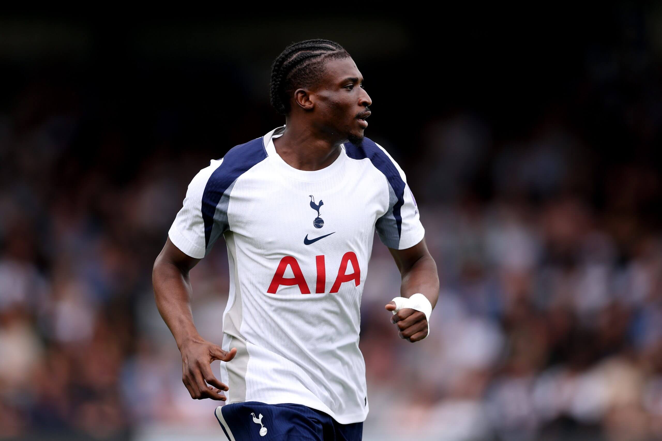 Tottenham Hotspur's star signing Mohammed Kudus looks focused during a Premier League fixture. The Ghanaian international, who moved to North London for £55 million, wears the iconic white Spurs home jersey featuring the AIA sponsor logo. Image used for Sportxparte news.